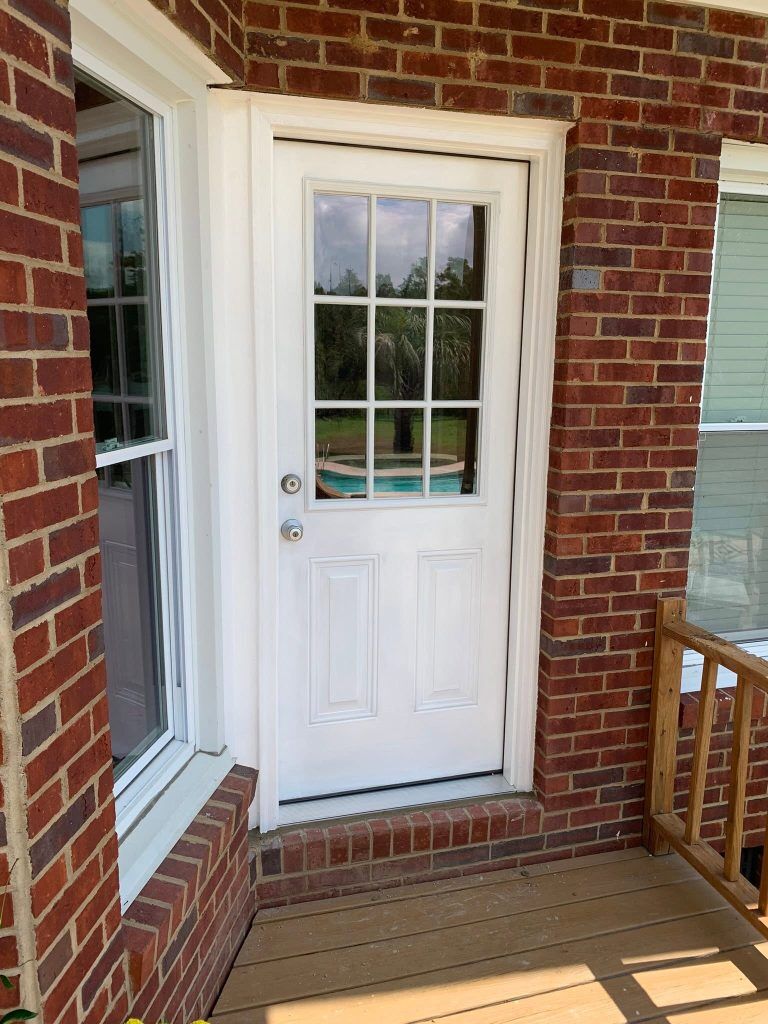 New exterior door installed on a brick home beside a wooden deck