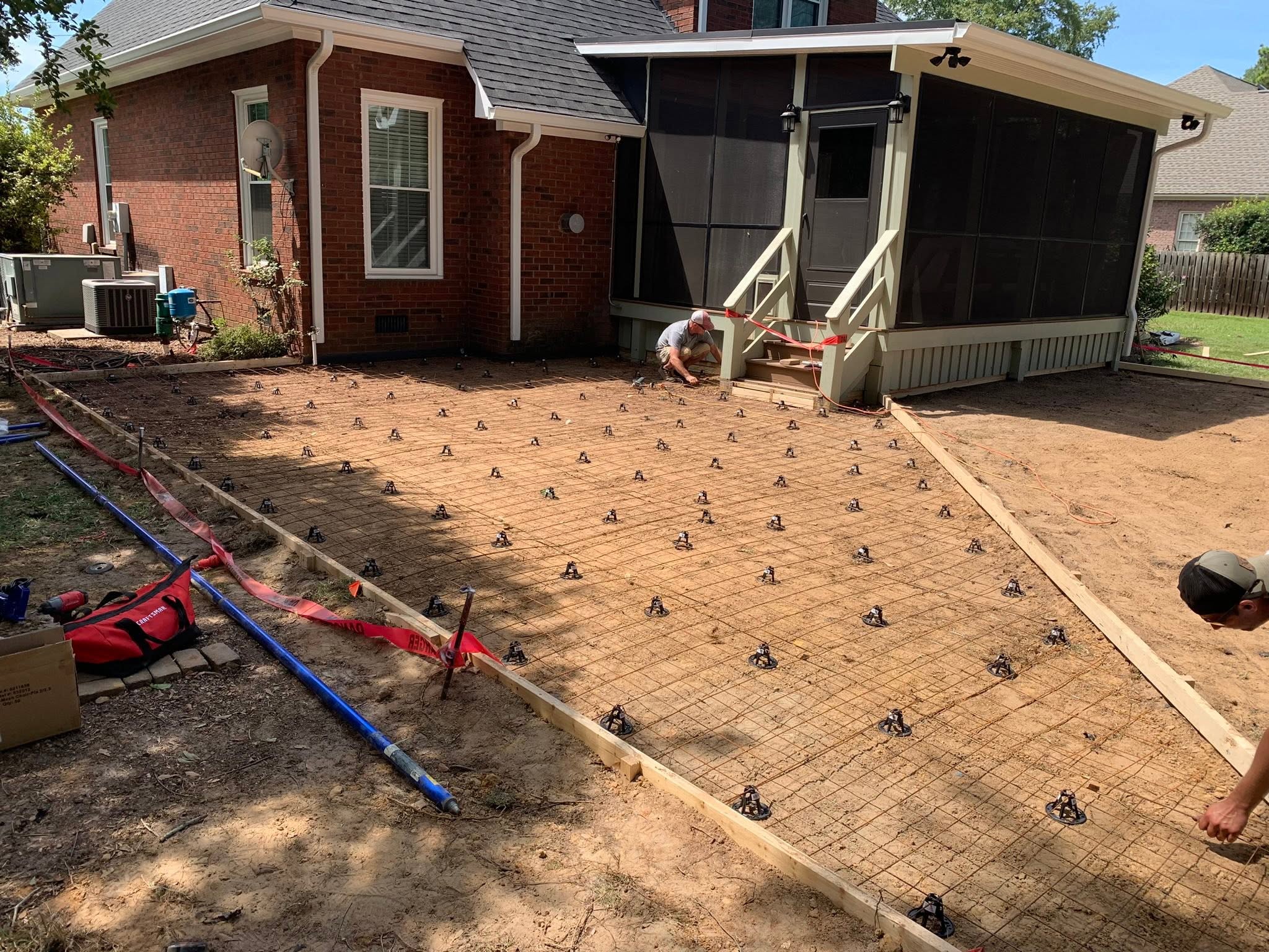 Crew preparing a reinforced concrete slab for a backyard patio addition