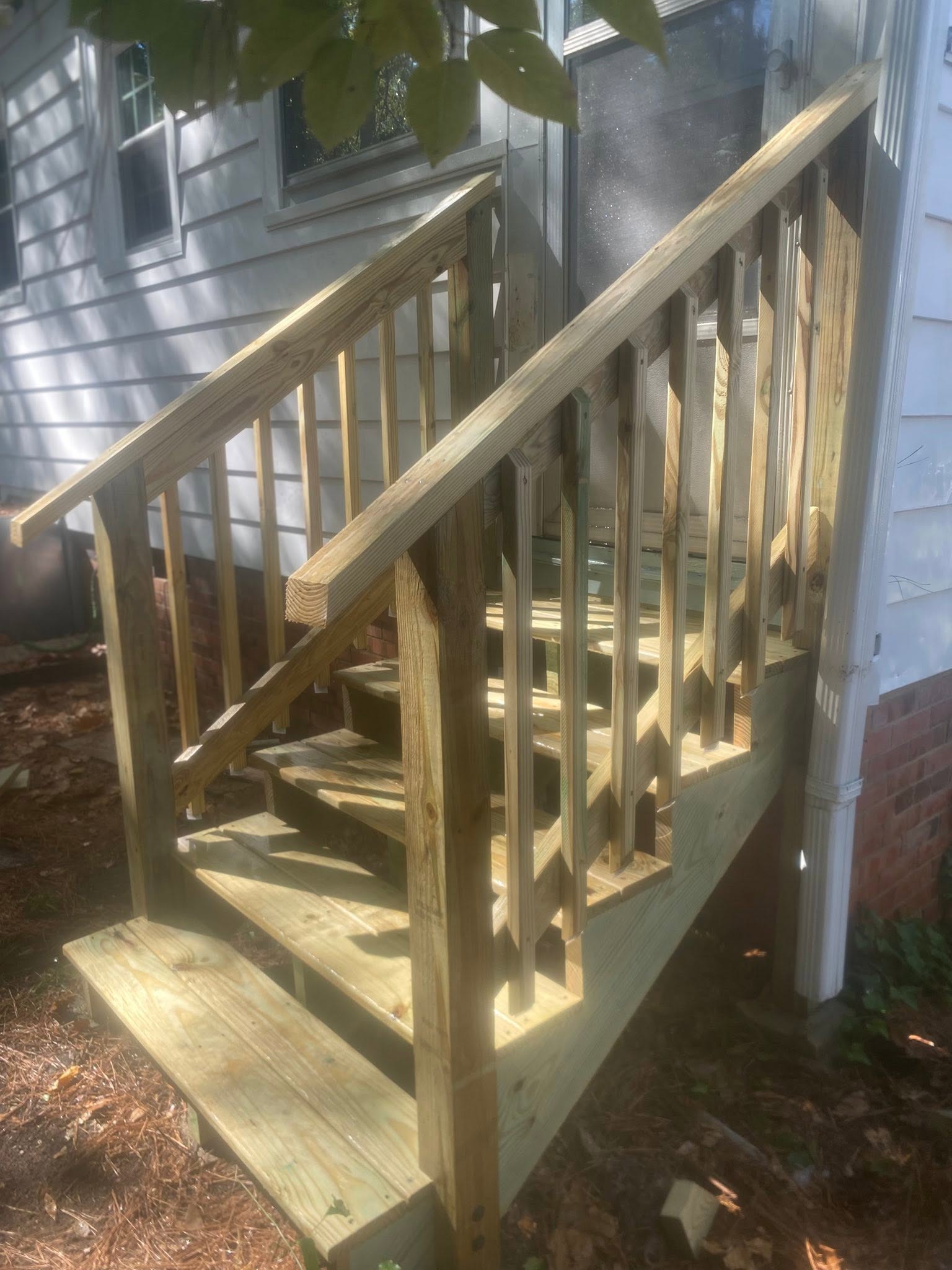 New pressure-treated wood steps and railing installed at a home entrance